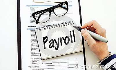 PAYROLL text written by business woman in her diary on office desk Stock Photo