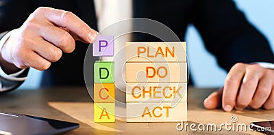 PDCA Cycle Management concept. man stacks wooden blocks with the inscription PDCA. Stock Photo