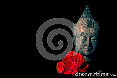 Peace and love. Traditional meditating Buddha head with red roses Stock Photo