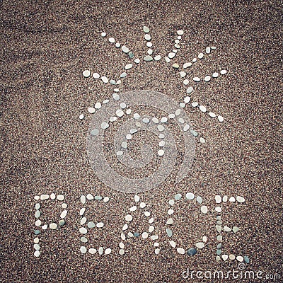 Peace word and sun symbol on the sand - toned photo. Stock Photo