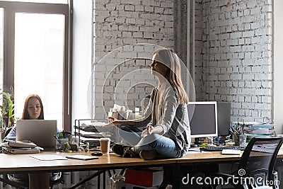 Peaceful businesswoman meditating on office desk, stress relief concept Stock Photo