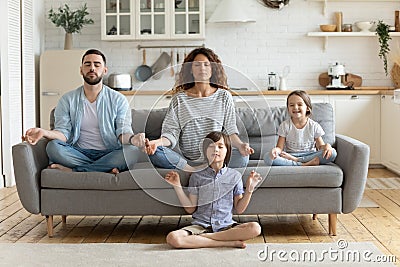 Peaceful calm couple practicing yoga exercises with small children. Stock Photo
