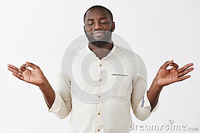 Peaceful and delighted African-american bearded male feeling nirvana smiling from pleasure as meditating with lotus pose Stock Photo