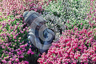 Peaceful garden. Traditional serene buddha statue ornament with beautiful flowers Stock Photo