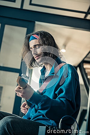 Peaceful handsome young man in bandana focusing on abilities of his instrument Stock Photo