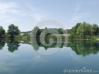 Peaceful lake with clouds and trees reflected in water Stock Photo