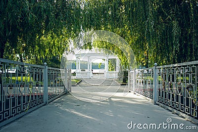 Peaceful morning park outdoor symmetry nature landscape with path through bridge to marble gazebo under trees arch on beautiful Stock Photo