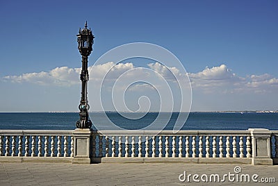 Peaceful scene with decorated street lamp and white handrail on the seaside in the Spanish city of Cadiz next to the sea Stock Photo