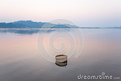 Peaceful serene by river, a bamboo basket is dipping in the Mekong River on winter morning, still life in rural Laos Stock Photo