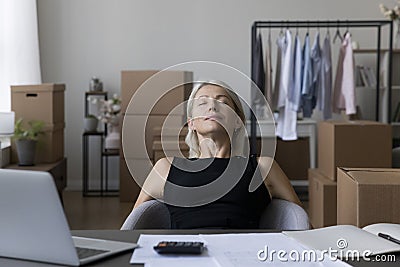 Peaceful tired mature entrepreneur woman relaxing at storage workplace Stock Photo