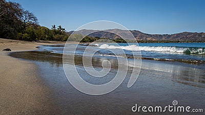 A peaceful tropical image of waves crashing onto a smooth sand beach in Costa Rica. Stock Photo