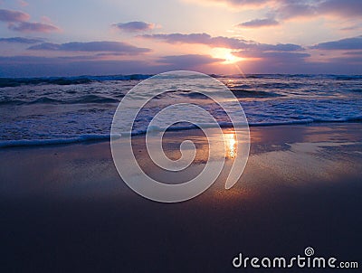 Peaceful view of a cloudy sunset on sandy beach with beautiful reflections on the wet sand Stock Photo