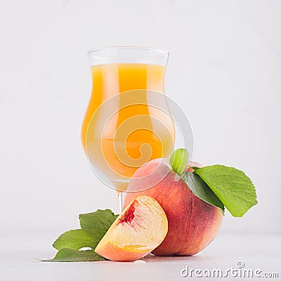 Peach juice in elegance glass with juicy piece peaches on light white wood table, closeup, square. Stock Photo