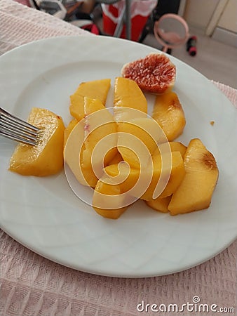 Peach sliced to eat easily on a plate and also a slice of fig summer fruits Stock Photo