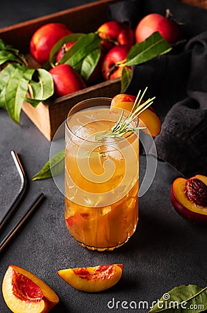 Peach tea with ice and rosemary on a tall glass. Vegan homemade healthy drink on a dark background with fresh fruits Stock Photo