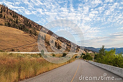PEACHLAND, CANADA - AUGUST 01, 2020: asphalt road between mountain and okanagan lake beautiful landscape with cloudy sky Editorial Stock Photo