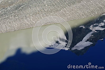 The peak of Grossglockner mountain is reflected in the water collected from the melting Pasterze glacier. Stock Photo