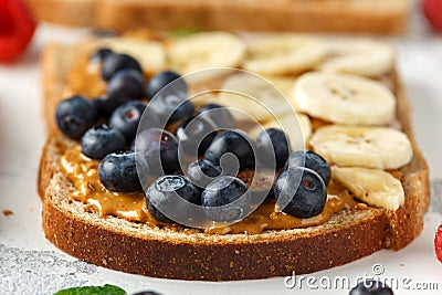 Peanut butter sandwiches with fresh strawberry, blueberry, raspberry and banana whole meal toasts. Stock Photo