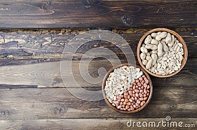 Peanuts on a wooden background. Unpeeled, peeled and salted peanuts Stock Photo
