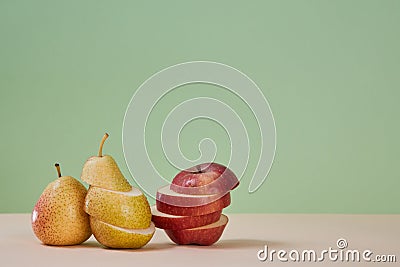 Pear and apple divided on slices. Juicy mellow fruits. Summer harvest. Healthy lifestyle. Copy space. Green background Stock Photo