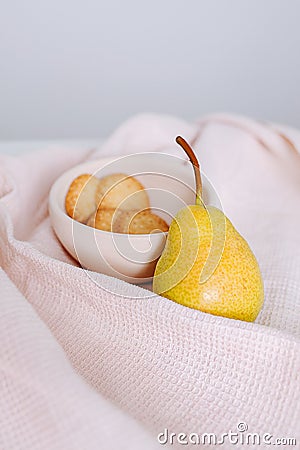 Pear and cookies on a bowl on a crumpled tablecloth with checkered texture Stock Photo