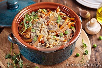 Pearl barley grain porridge with carrot, mushrooms, green peas and onion Stock Photo