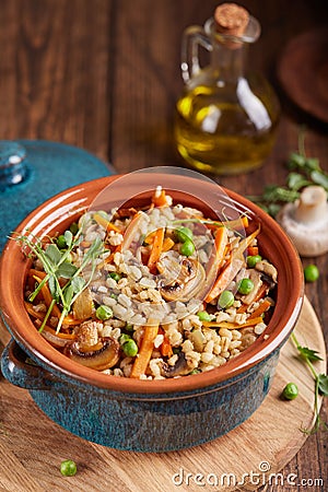 Pearl barley grain porridge with carrot, mushrooms, green peas and onion Stock Photo