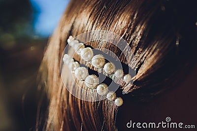 Pearl and filagree hair clasp in beautiful long reddish brown hair - close up. Stock Photo