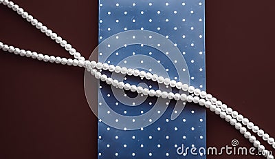 Pearl jewellery necklace and abstract blue polka dot background on chocolate backdrop Stock Photo