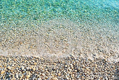 Pebble beach with azure sea water texture Stock Photo