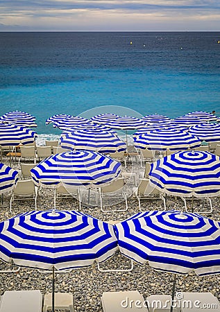 Pebble beach with beach umbrellas and chairs on Mediterranean Sea in Nice France Stock Photo