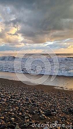 Pebble beach on the sea coast and cloudy sky Stock Photo