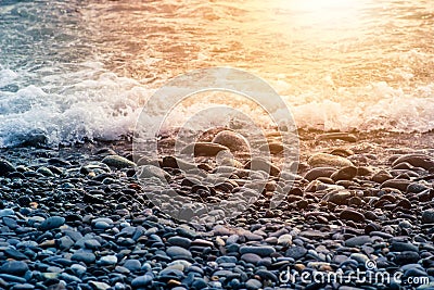 Pebble stones on the shore close up in the blurry sunset light in the distance background Stock Photo