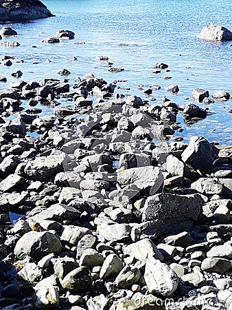 Pebble beach and blue sea against Stock Photo