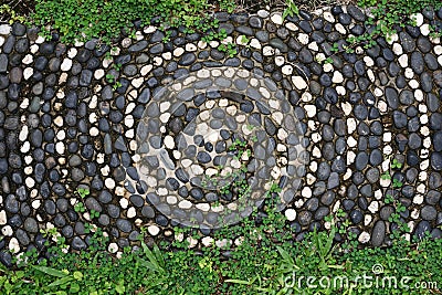 Pebbles mosaic floor with spiral pattern and plant Stock Photo