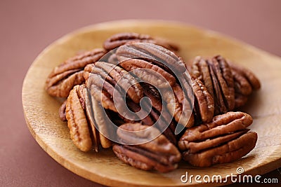 Pecan nut close-up in spoon on brown background.Healthy fats.Heap shelled Pecans nut closeup. Ingredient of the keto Stock Photo