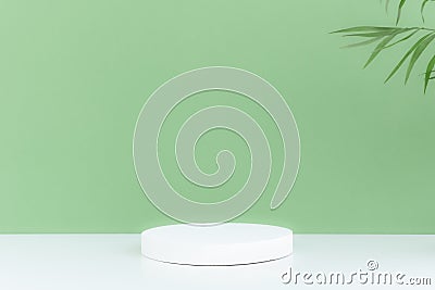 Pedestal podium on a white table, green background with palm tree leaves Stock Photo