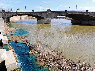 Pedestrian bridge in White River State Park Indianapolis Indiana with muddy and vivid blue water mixing Stock Photo