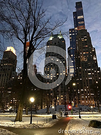 Pedestrian walks in New York`s Central Park against the backdrop of Manhattan skyscrapers in the evening in winter Editorial Stock Photo
