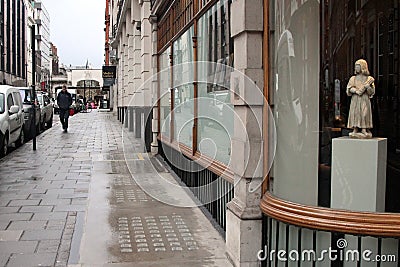 A pedestrian walks past the art galleries along Cork Street on a damp day in London, UK Editorial Stock Photo