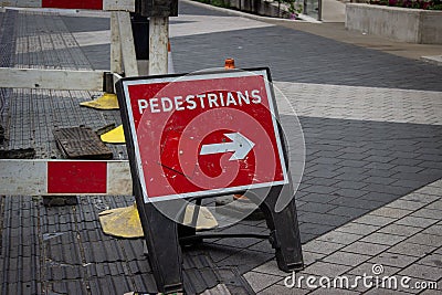Pedestrians with arrow roadwork sign on street Stock Photo
