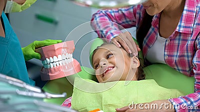 Pediatric dentist showing little smiling girl artificial jaw model, education Stock Photo