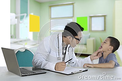 Pediatrician checking tongue of a patient in clinic Stock Photo