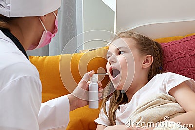Pediatrician doctor using medical spray for young girl at home, sore throat Stock Photo