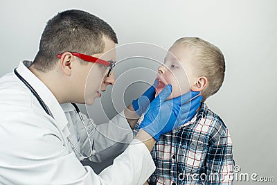 A pediatrician examines a boy who complains of a sore throat. Diagnosis of tracheal diseases. Angina, tonsillitis, pharyngitis, Stock Photo