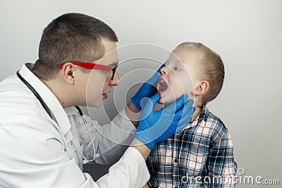 A pediatrician examines a boy who complains of a sore throat. Diagnosis of tracheal diseases. Angina, tonsillitis, pharyngitis, Stock Photo