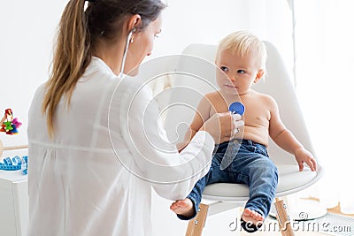 Pediatrician examining baby boy. Doctor using stethoscope to listen to kid Stock Photo