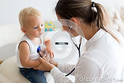 Pediatrician examining baby boy. Doctor using stethoscope to listen to kid Stock Photo