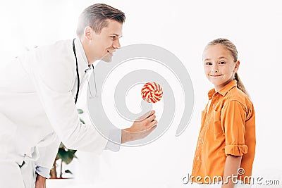 Pediatrist in white coat giving candy to child Stock Photo