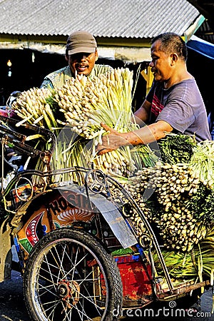 Pedicab driver and customer unload lemon grass. Editorial Stock Photo